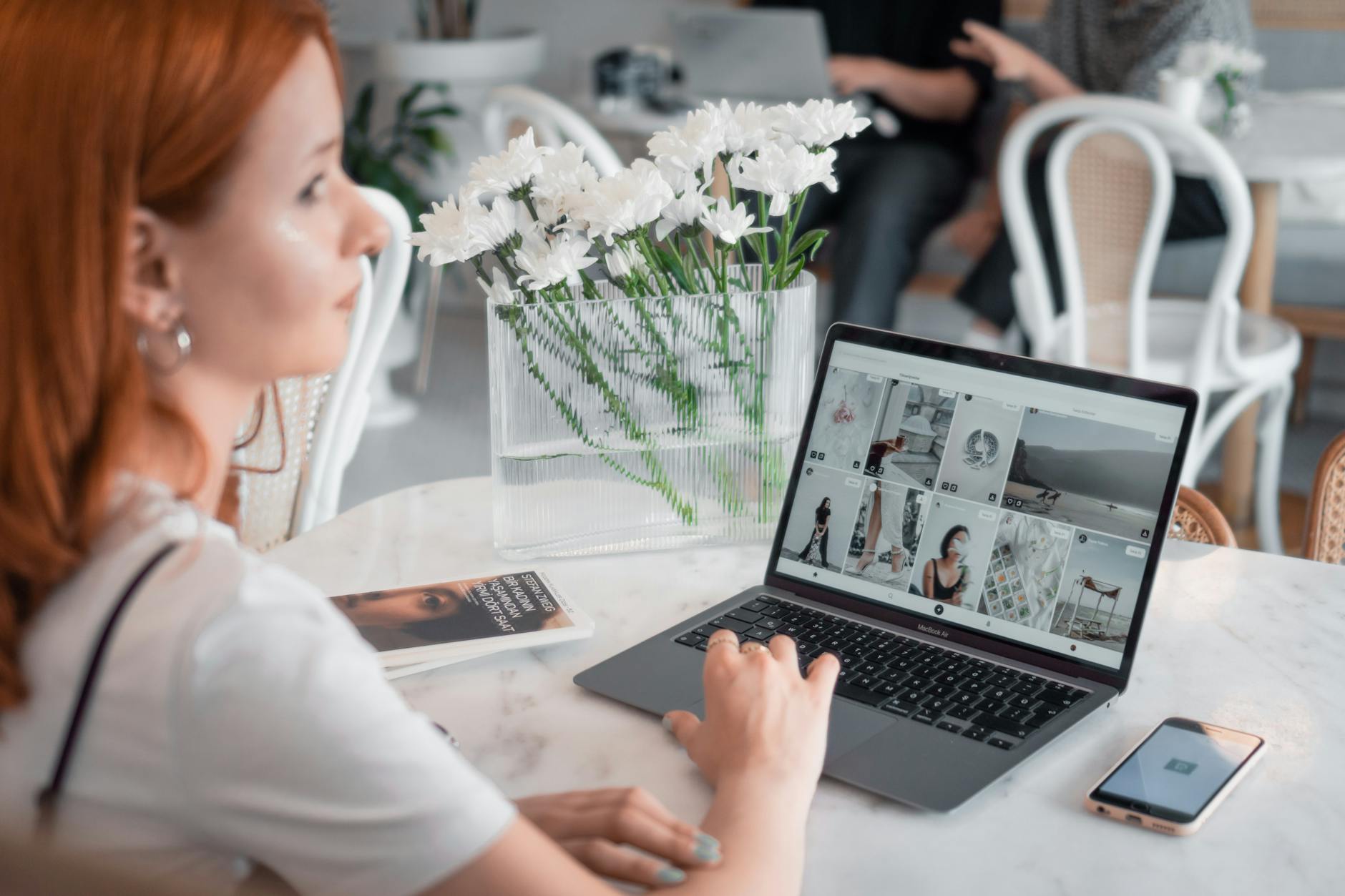 Freelancerka z rudymi włosami pracuje na laptopie w nowoczesnej kawiarni