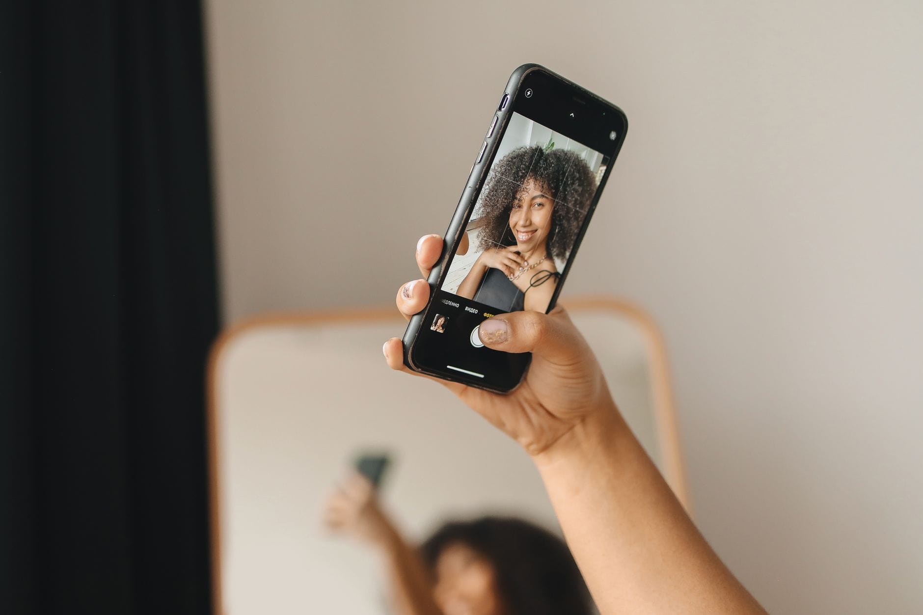 Kobieta uśmiecha się, robiąc selfie smartfonem w pomieszczeniu