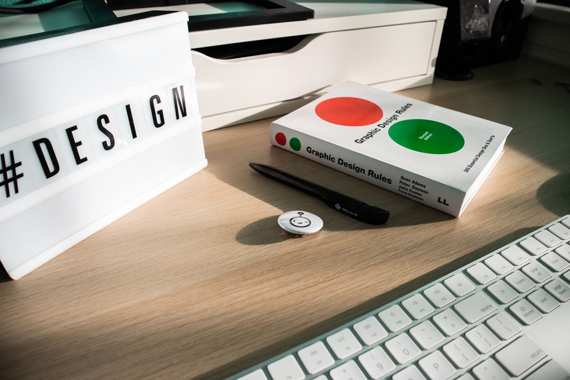 Nowoczesne biurko z książką, napisem DESIGN i akcesoriami